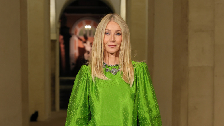 Gwyneth Paltrow smiling with her mouth closed wearing a green dress.