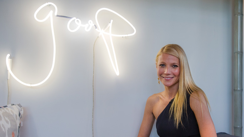Gwyneth Paltrow posing with a neon Goop sign