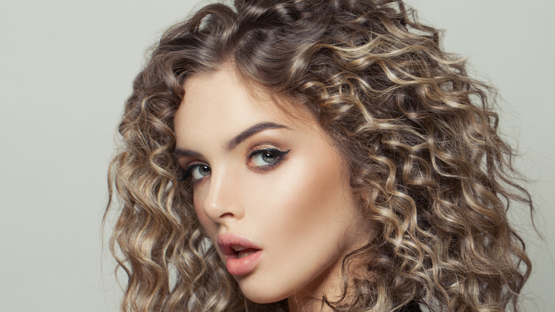 A woman with curly brown hair and blonde highlights