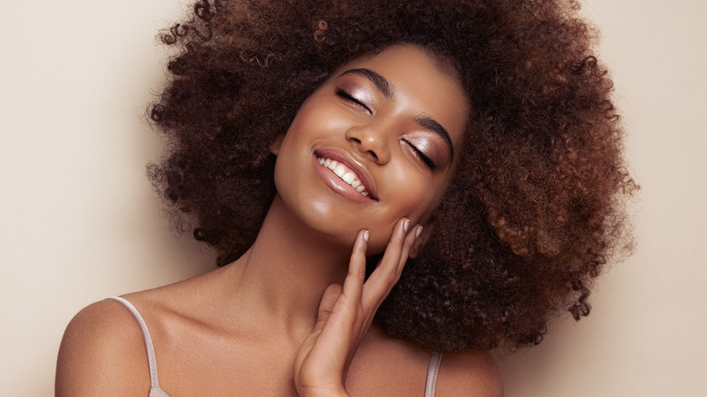 Woman with curly hair touching face