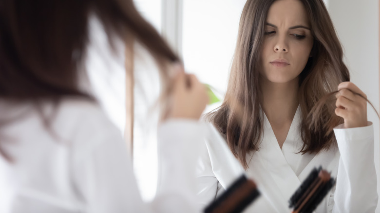 woman looking at hair with worry 