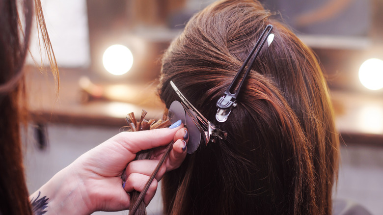 Hairstylist putting hair extensions in client's hair