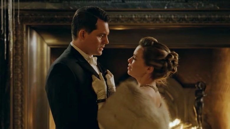Bethany Joy Lenz and Kristoffer Polaha smiling at each other outside of a lit-up building