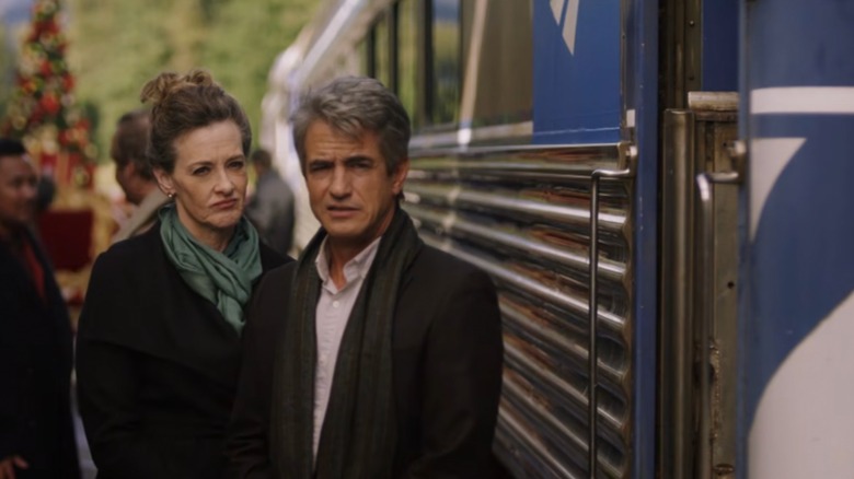 Dermot Mulroney and Joan Cusack looking in the distance next to a train
