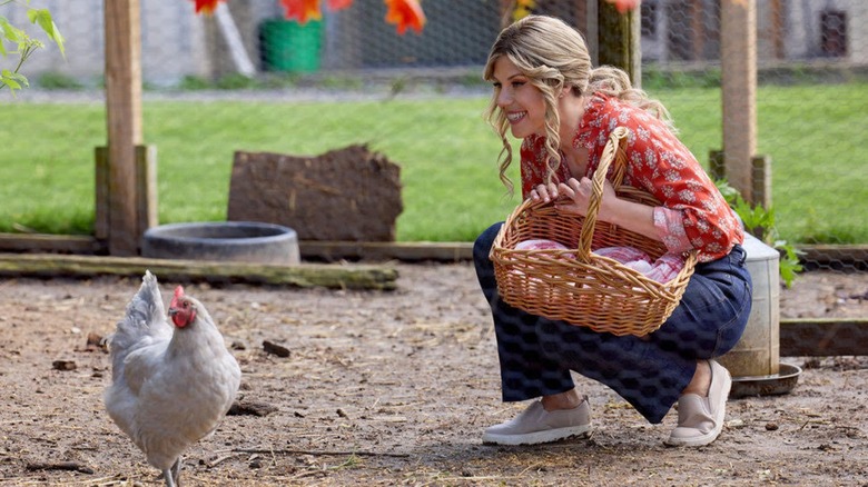 Jodie Sweetin kneeling down to greet a chicken