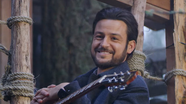 Tyler Hynes smiling while holding a guitar