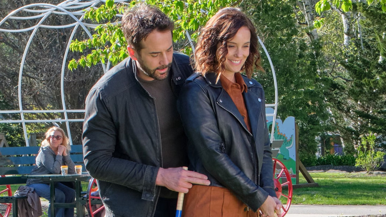 Niall Matter guiding Ashley Williams as she plays croquet in "Much About Love"