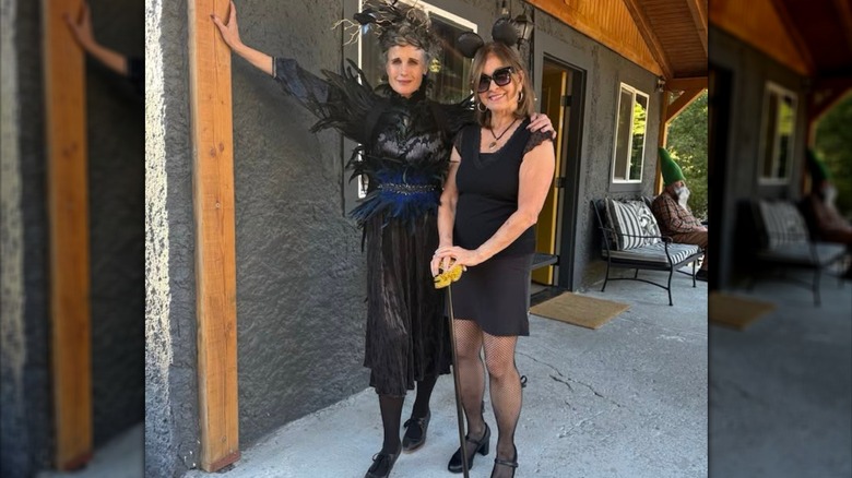 Andie MacDowell wearing a black feathered dress and posing with her sister Julia outdoors.