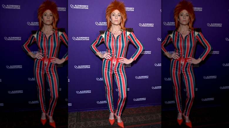 Nikki DeLoach posing with her hands on her hips in a striped David Bowie costume and red wig.