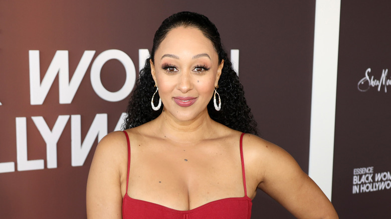 Tamera Mowry-Housley posing in front of a Women in Hollywood background