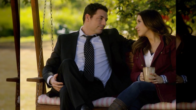 Lacey Chabert and Brennan Elliott looking at each other on a swing