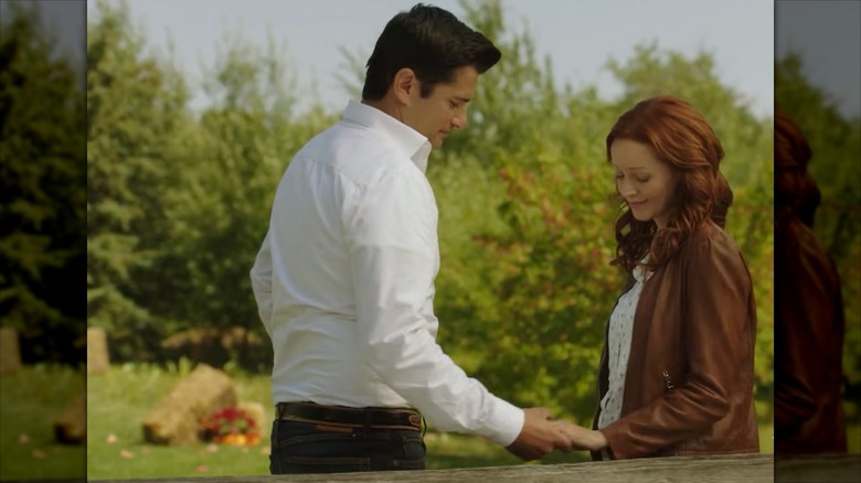Lindy Booth and Wes Brown holding hands and looking down