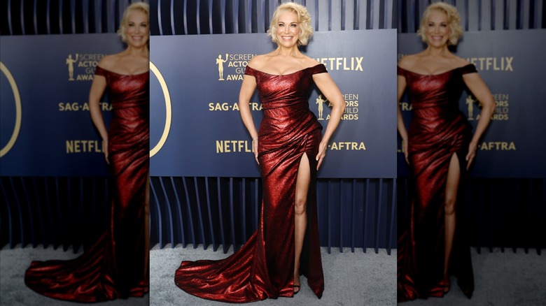 Hannah Waddingham posing in a red dress with a train and side slit.