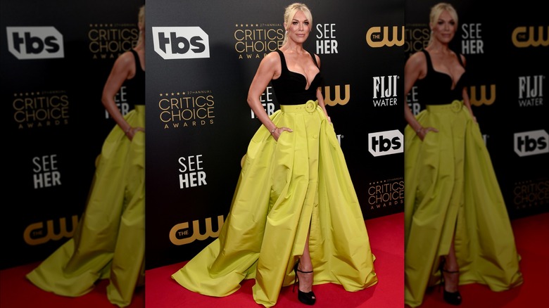 Hannah Waddingham posing in a black top and a green skirt with pockets.