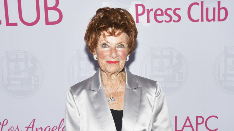 Marion Ross in silver blazer posing in front of a "Press Club" backdrop.