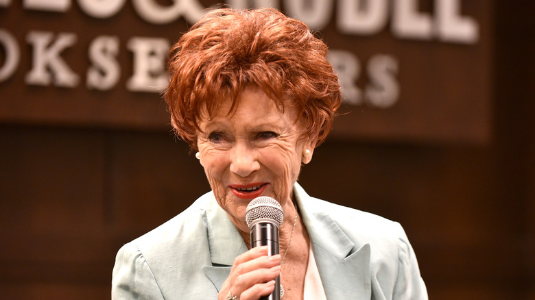 Marion Ross in grey outfit with a microphone in hand