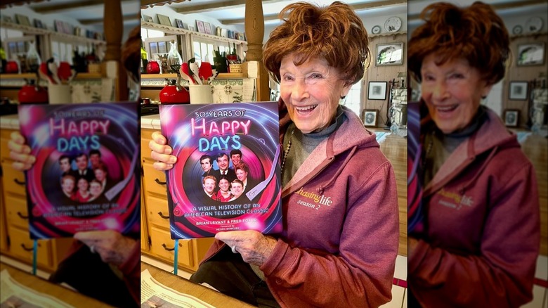 Marion Ross holding up a book titled 50 Years of Happy Days.