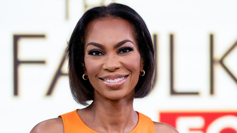 Harris Faulkner smiling in an orange and black dress while on 'The Faulkner Focus.'
