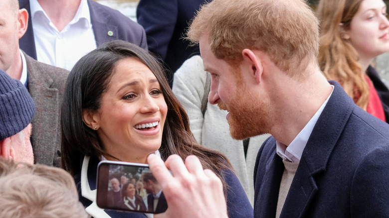 Prince Harry and Meghan Markle laughing with royal fans 