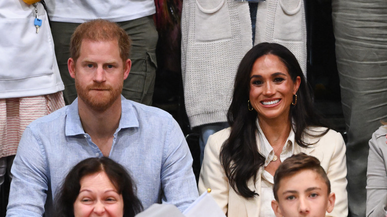 Focused Prince Harry and grinning Meghan Markle