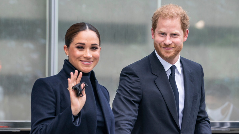 Meghan Markle smiles and waves beside Prince Harry