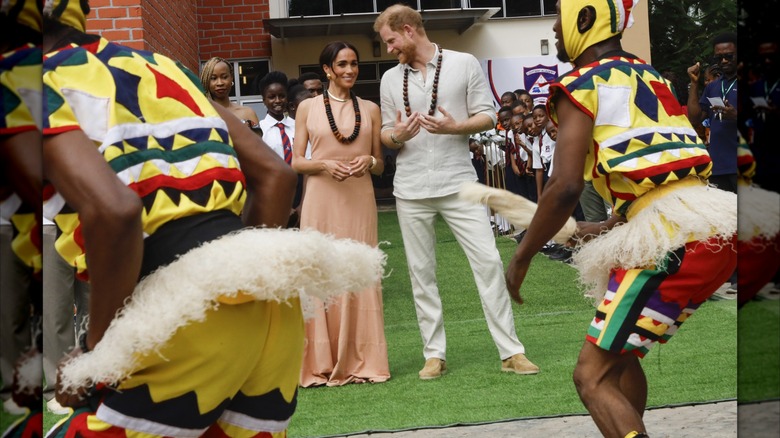 Meghan Markle and Prince Harry talk while watching a performance in Nigeria