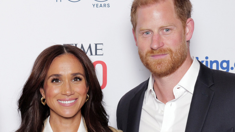 Prince Harry and Meghan Markle smiling while posing for photos at an event