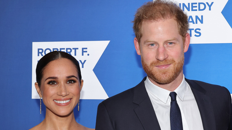 Prince Harry and Meghan Markle smiling while posing at an event
