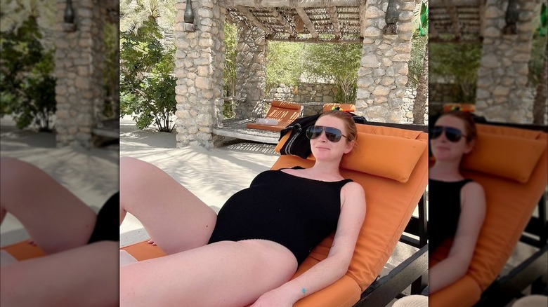 Lindsay Lohan pregnant and wearing a black one-piece bathing suit