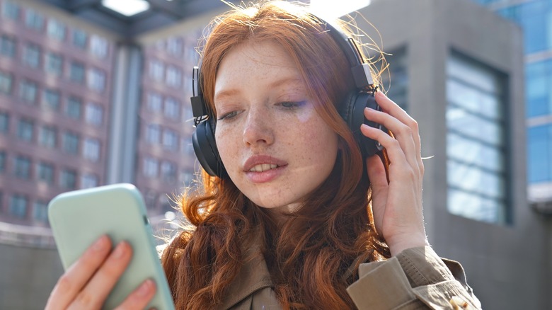 woman wearing headphones holding phone