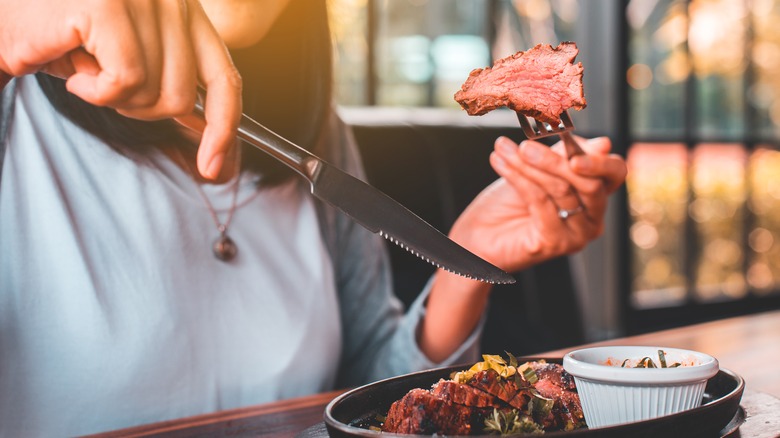 Woman eating steak at restaurant 