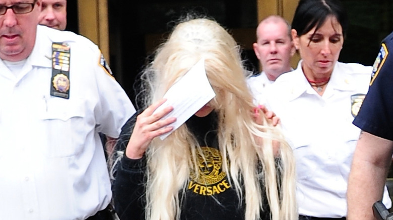 Amanda Bynes walking and covering her face with a sheet of paper in May 2013