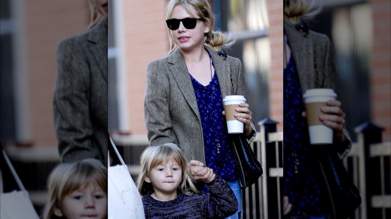 Matilda Ledger and Michelle Williams with a beverage in hand walking in Brooklyn