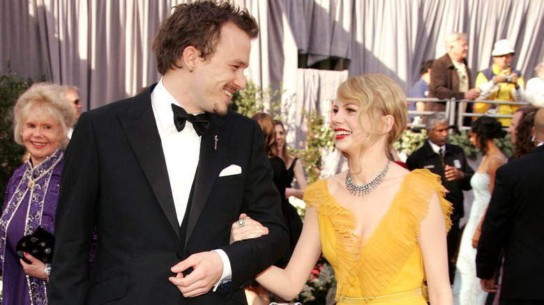Heath Ledger and Michelle Williams smiling at each other at the 78th Academy Awards red carpet