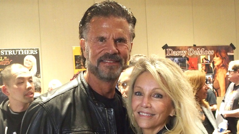 Lorenzo Lamas in a leather jacket posing with Heather Locklear wearing big hoop earrings.