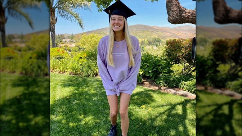 Ava Sambora smiles with a graduation cap and sweater on