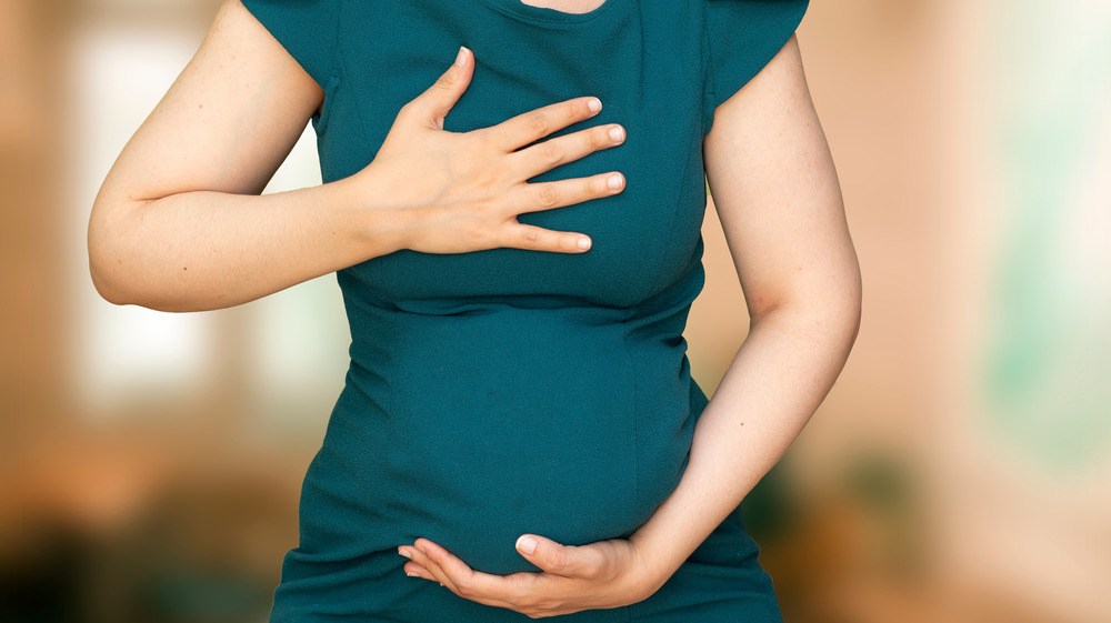 Pregnant woman holding chest and belly