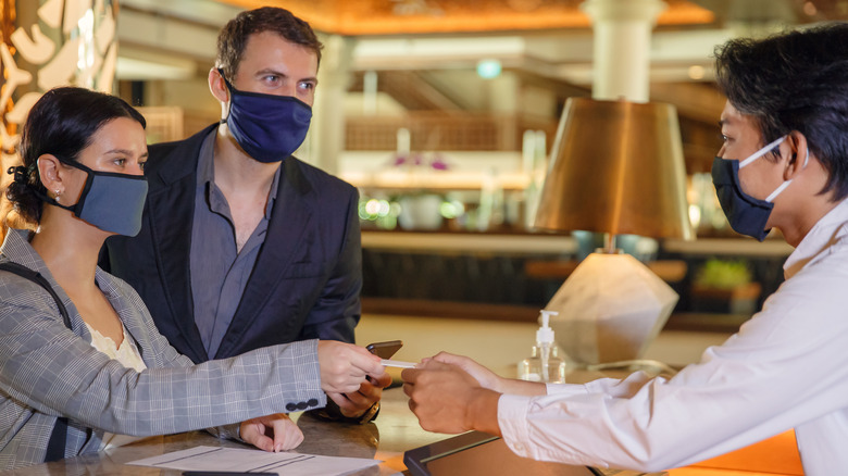 Couple in masks checking into hotel