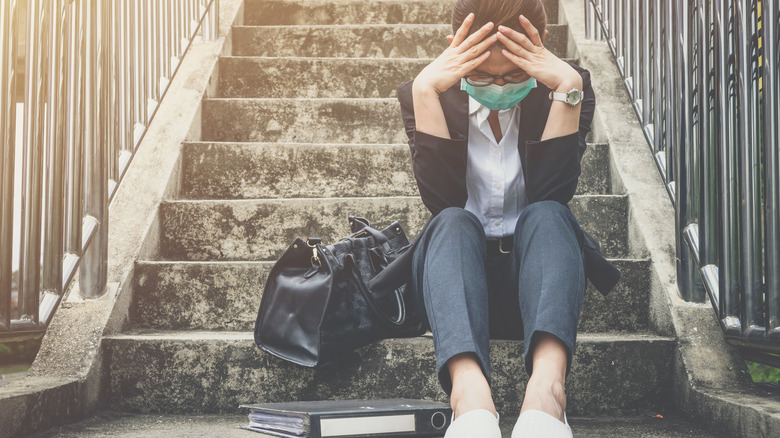 Woman on steps holding head