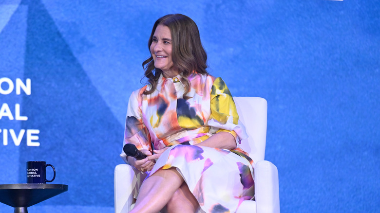Melinda French Gates wearing a water color pattern dress sitting on a couch