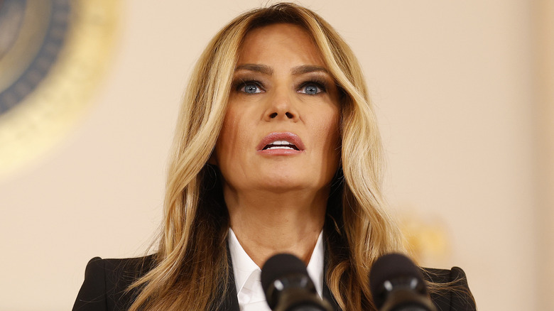 Melania Trump looking shocked while standing in front of a microphone
