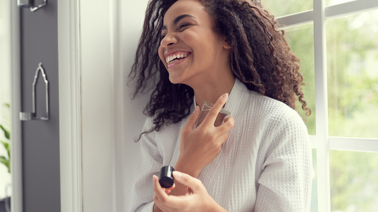 woman spraying perfume on neck