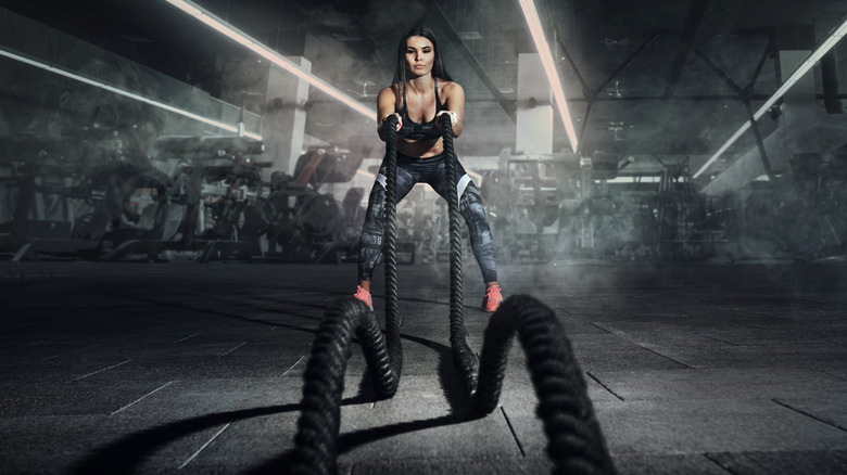 Athletic woman using battle ropes