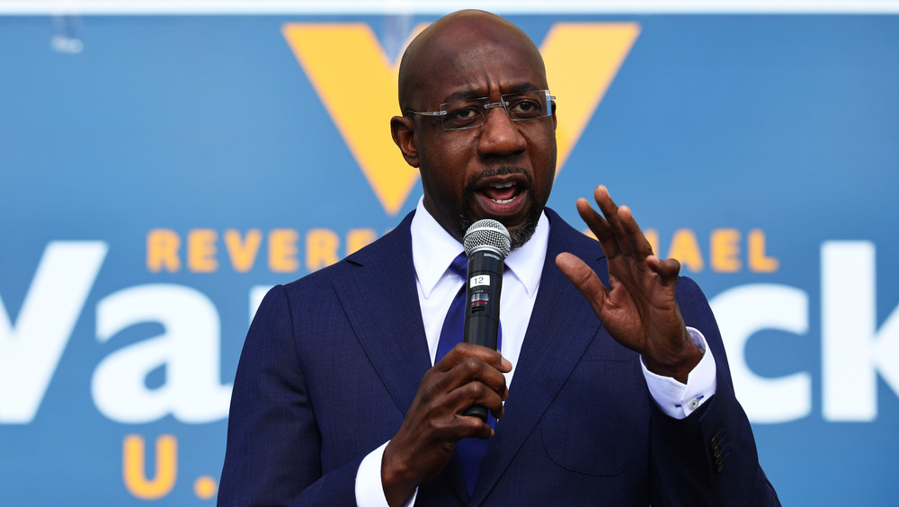 Raphael Warnock speaking at rally in blue suit