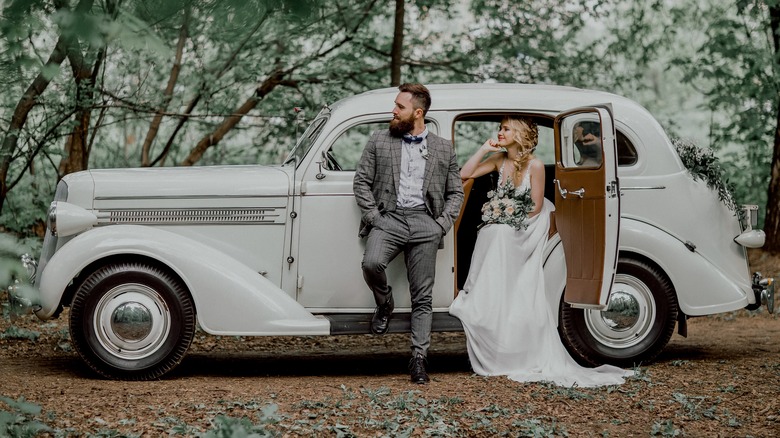 Bride and groom standing next to vintage car