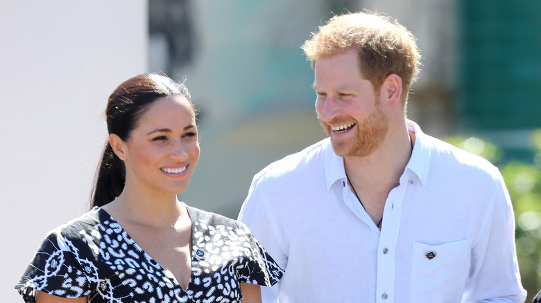 Prince Harry and Meghan Markle smile at an event.