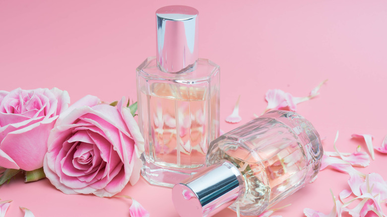 Perfume bottles and roses on a pink background