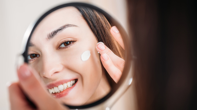 Woman rubbing cream on her skin