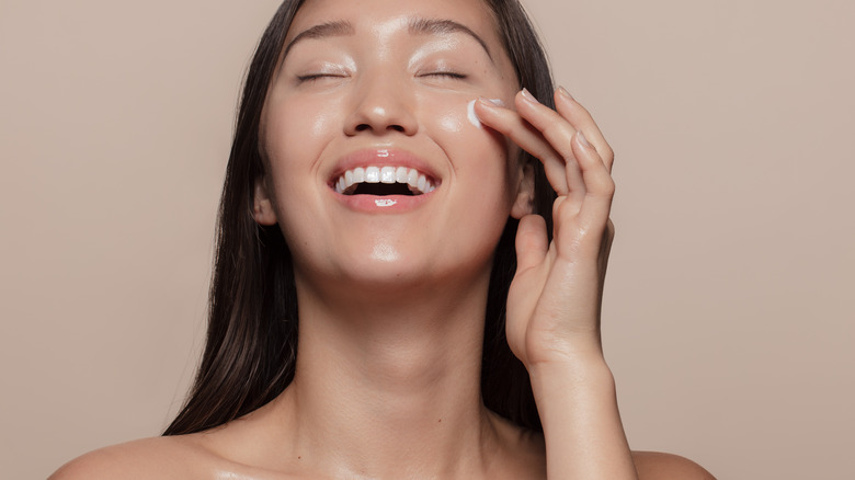 A woman applies face cream