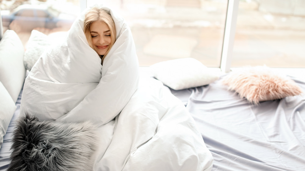 Woman snuggling in white duvet